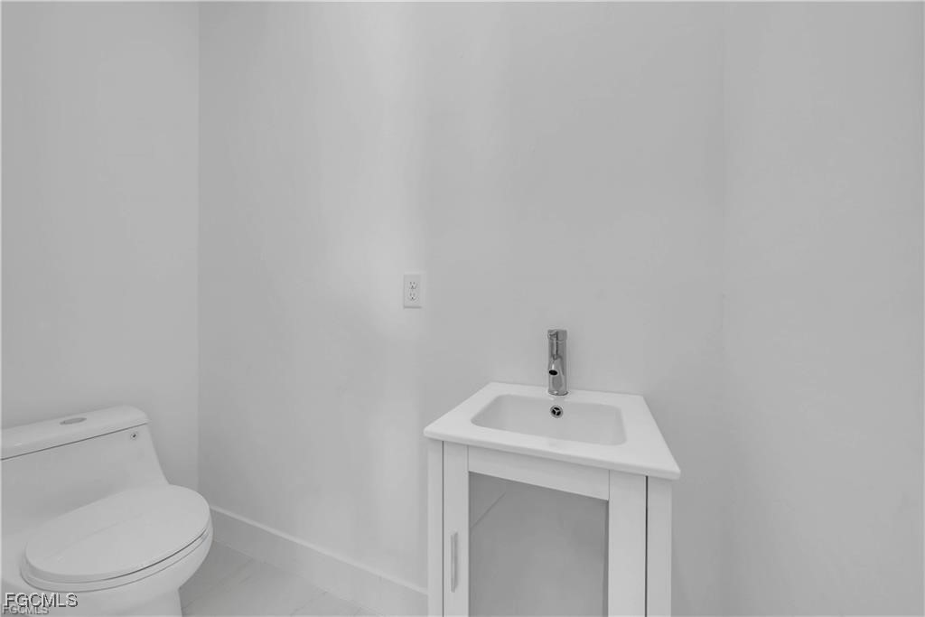 3310 11th Street West Lehigh Acres, FL 33971 - Photo 17 of 20 a bathroom with a toilet a sink and mirror