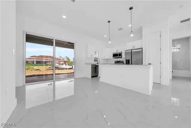 a large white kitchen with a large window and stainless steel appliances