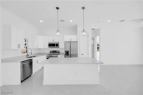 a large kitchen with stainless steel appliances kitchen island a large counter top and a sink