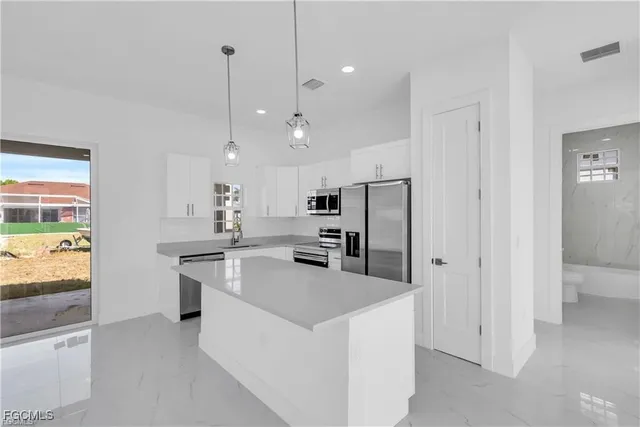 a kitchen with stainless steel appliances granite countertop a refrigerator a stove and a sink