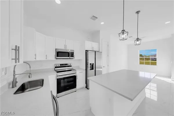 a kitchen with stainless steel appliances a stove a sink island and a refrigerator