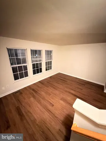 a view of an empty room with wooden floor and windows