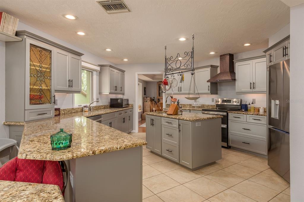 2279 Ranchette Lane Dunedin, FL 34698 - Photo 21 of 50 a kitchen with stainless steel appliances granite countertop a sink stove and refrigerator