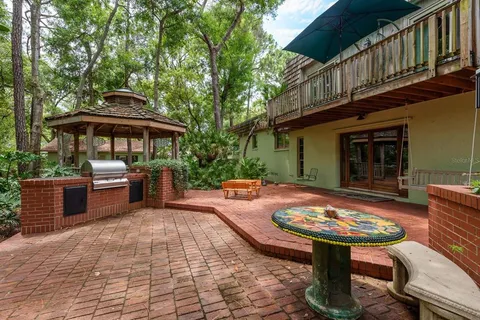 a view of a house with lots of plants and large trees