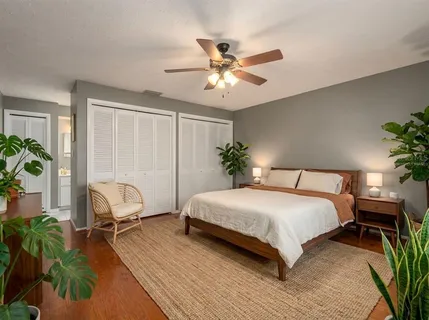 a bedroom with a bed table flowerpot and window
