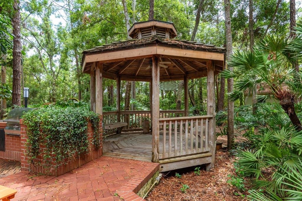 2279 Ranchette Lane Dunedin, FL 34698 - Photo 10 of 50 a view of a deck with a table and chairs under an umbrella with a small yard