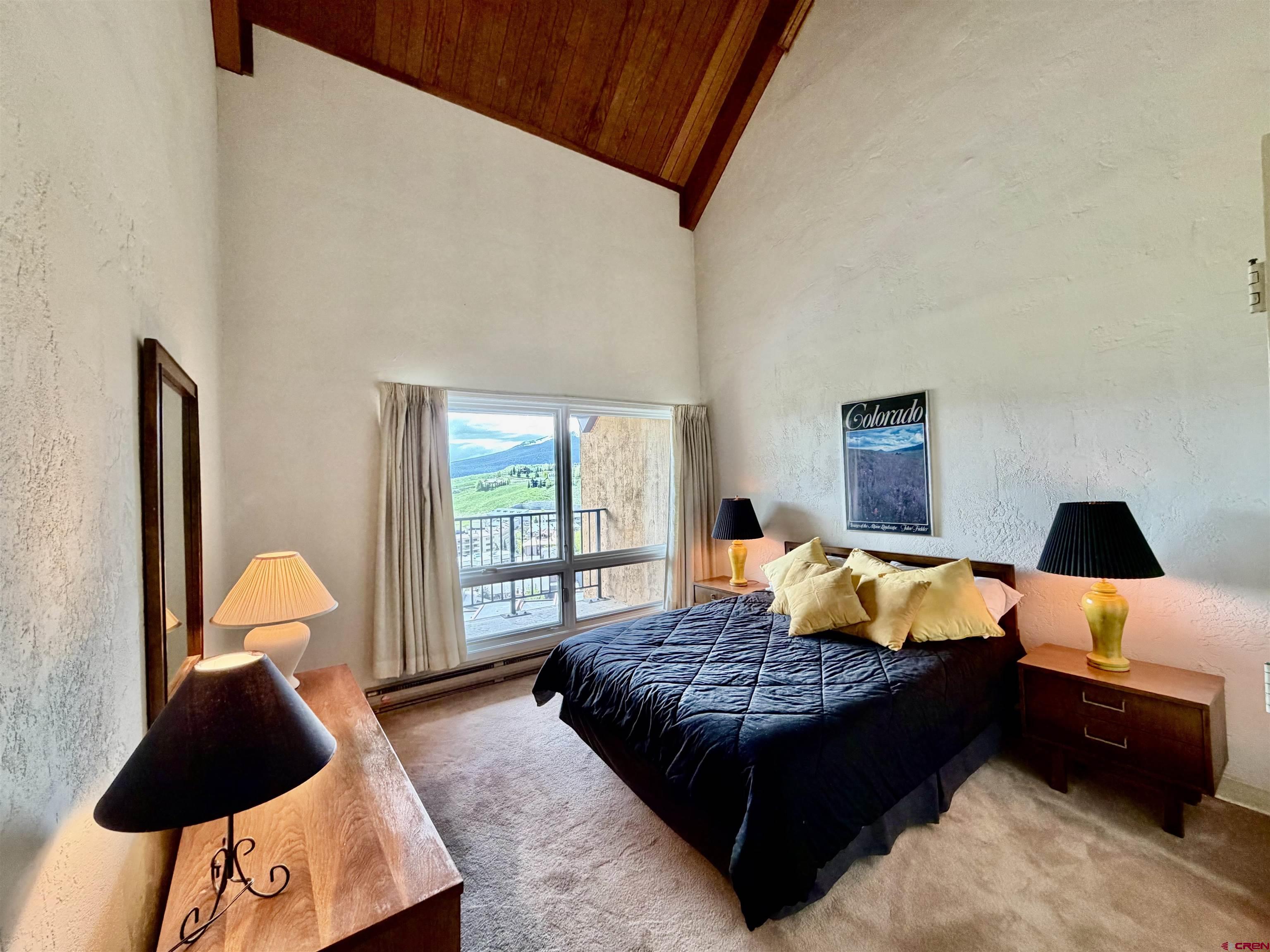 51 Whetstone Road, Unit 2306 Crested Butte, CO 81225 - Photo 22 of 44 a bedroom with a bed lamp and a large window