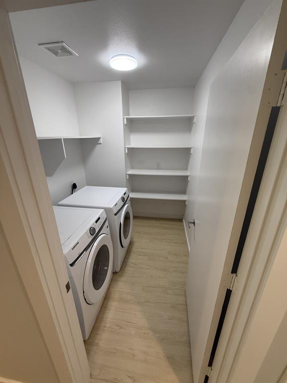 505 Thomas Street Terrell, TX 75160 - Photo 11 of 38 Dedicated laundry area featuring a washer and dryer, wood-finish flooring, built-in shelving, and overhead lighting
