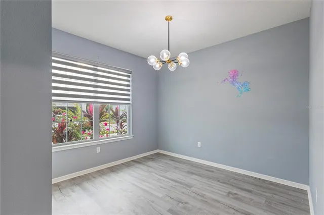 an empty room with wooden floor chandelier and window