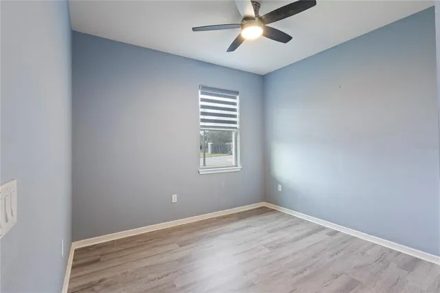 an empty room with a window and ceiling fan