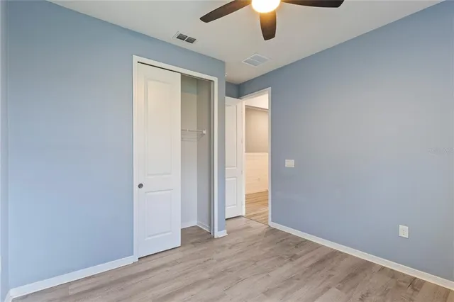 an empty room with a hardwood and ceiling fan
