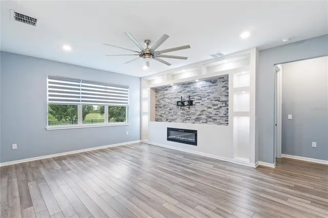 a view of empty room with wooden floor and fan