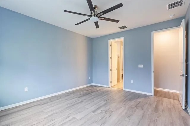 an empty room with wooden floor and a ceiling fan