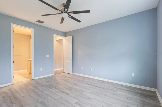 an empty room with wooden floor and a ceiling fan