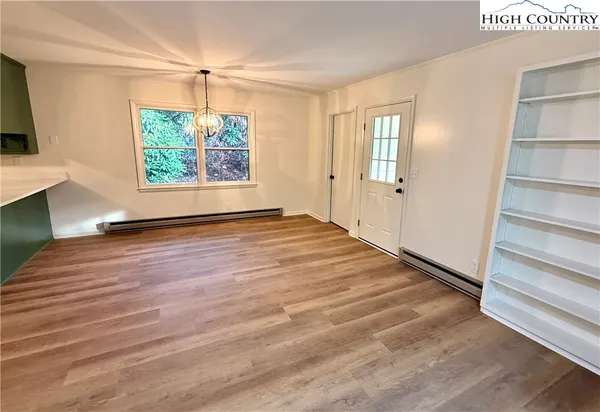 a view of an empty room with a window and wooden floor