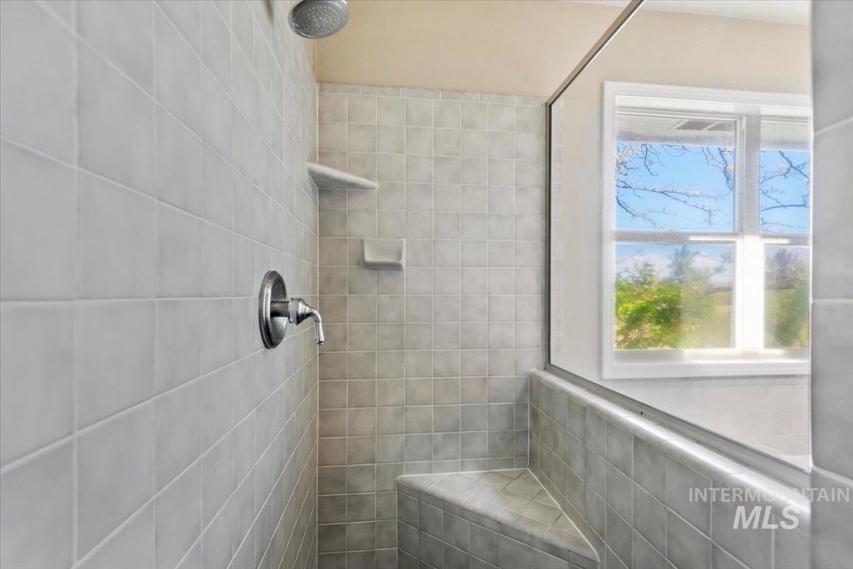 147 East Indian Crk Road Boise, ID 83716 - Photo 18 of 43 Tiled shower enclosure featuring a built-in bench, chrome fixtures, and a glass partition