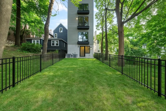 a view of a house with a small yard and large trees