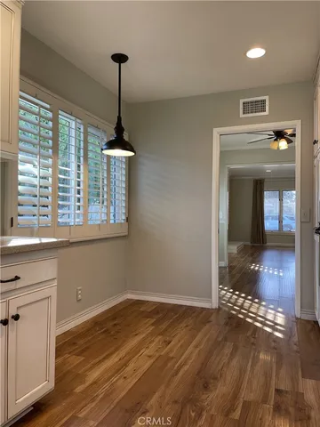 a view of empty room with wooden floor and fan