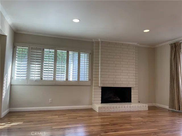 an empty room with wooden floor and fireplace