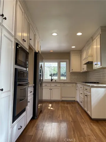 a kitchen with stainless steel appliances white cabinets and wooden floors