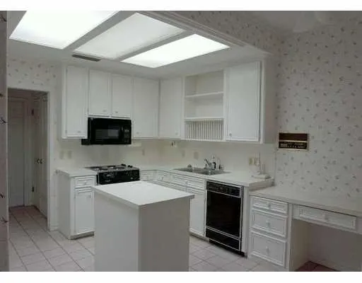 a kitchen with stainless steel appliances a sink dishwasher stove and microwave with wooden floor