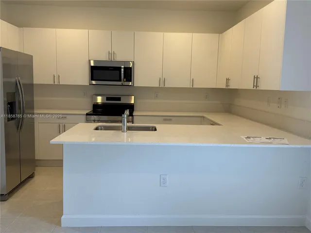 a kitchen with a sink a microwave a refrigerator and cabinets