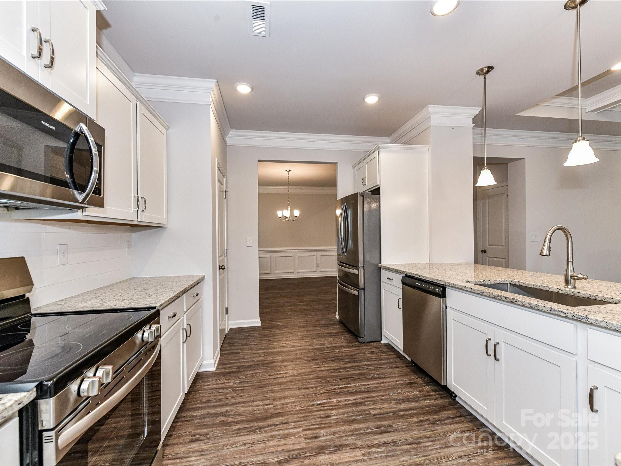 6168 Busch Way Midland, NC 28107 - Photo 11 of 42 a kitchen with stainless steel appliances granite countertop a sink and a stove top oven with wooden floor