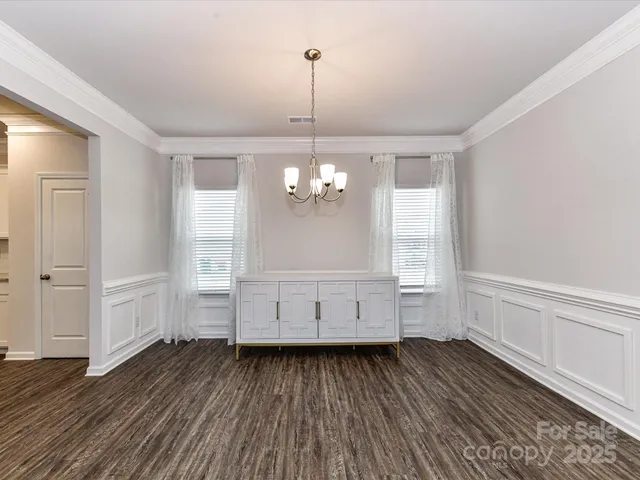 a view of a livingroom with wooden floor staircase and a kitchen space