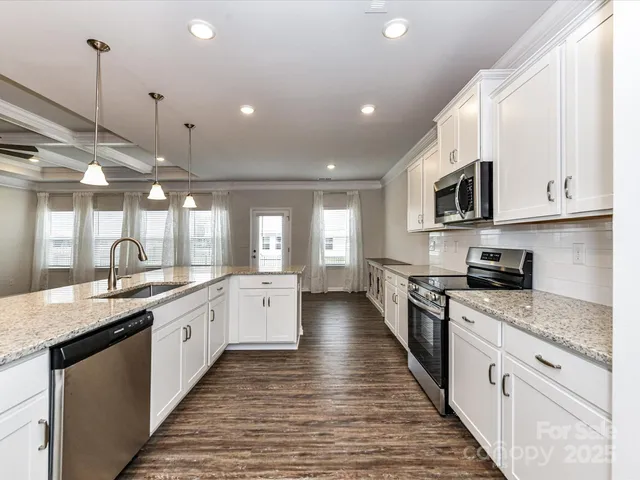a kitchen with stainless steel appliances granite countertop a sink and a stove top oven with wooden floor