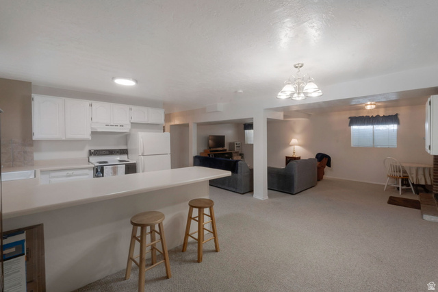 11072 Windy Peak Ridge Drive, Unit 32 Sandy, UT 84094 - Photo 25 of 30 Open-concept living space featuring a breakfast bar with solid surface countertop, white cabinetry with white appliances, and recessed lighting