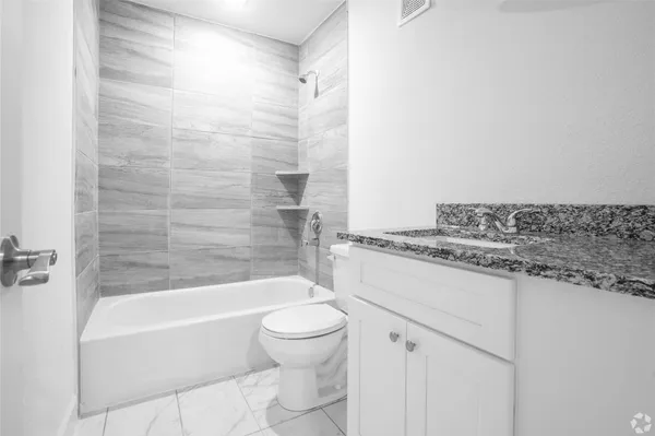 a bathroom with a granite countertop toilet a sink and bathtub