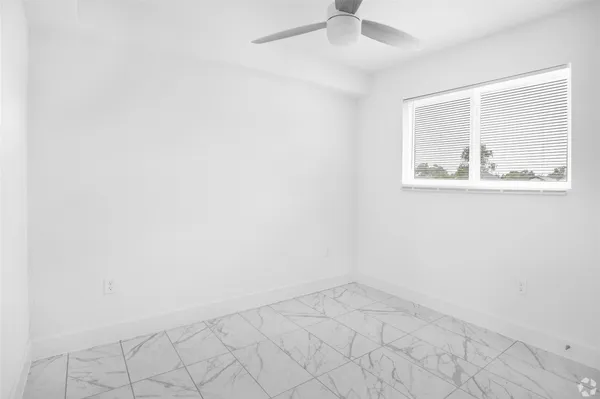 an empty room with a window and a fan
