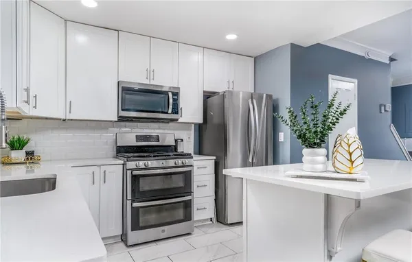 a kitchen with appliances a counter space and cabinets
