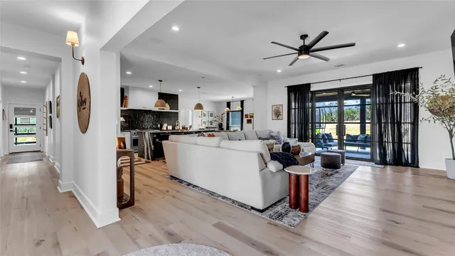 a living room with couches and kitchen view with wooden floor