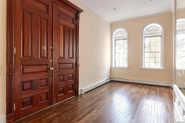 an empty room with wooden floor windows and closet