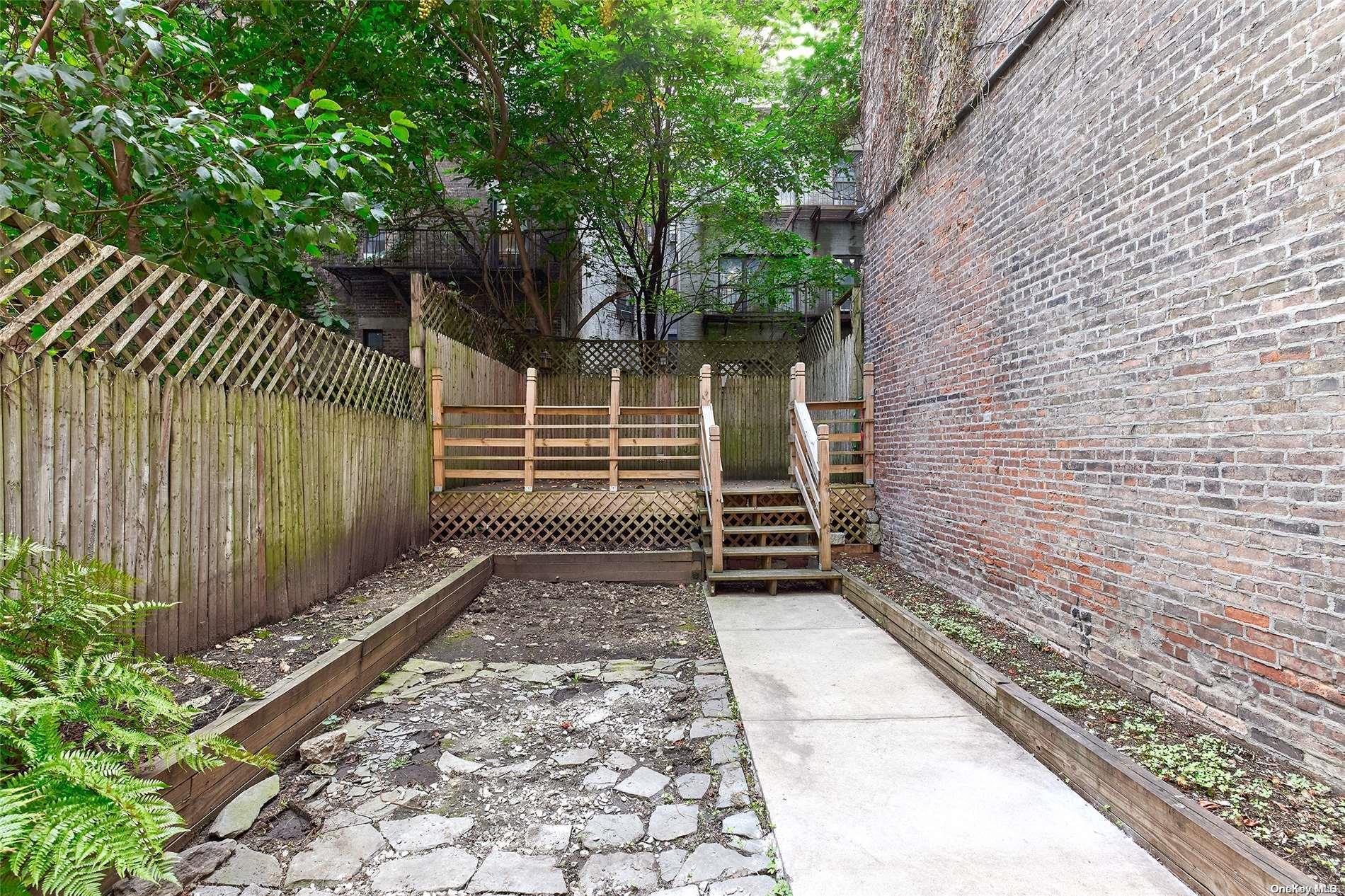266 West 136th Street Manhattan, NY 10030 - Photo 20 of 22 a view of a yard with an umbrella and wooden fence