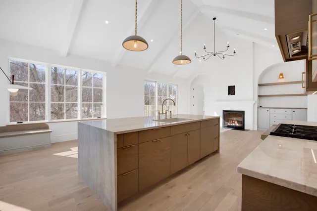 a large kitchen with stainless steel appliances a large counter top a stove a chimney a sink and a refrigerator