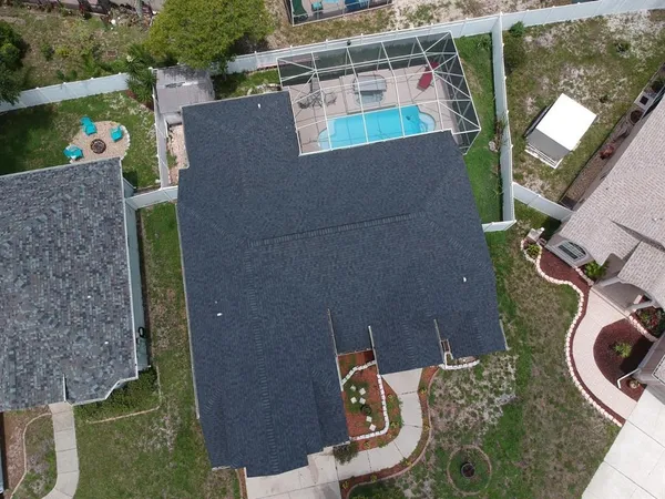an aerial view of a house with swimming pool and large trees
