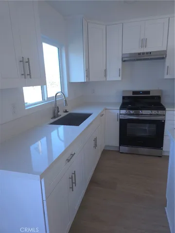 a kitchen with granite countertop a sink stove and cabinets