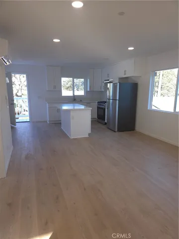 a living room with stainless steel appliances kitchen island furniture and windows