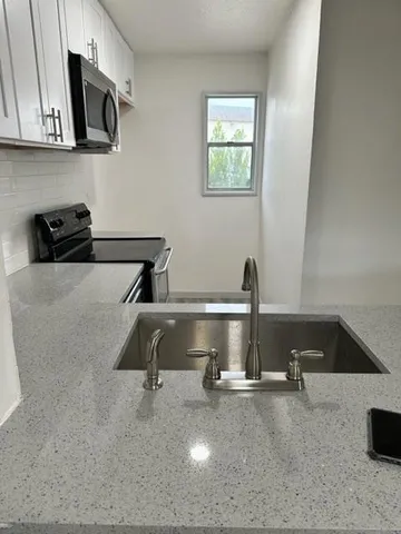 a room with kitchen island a stove and a sink