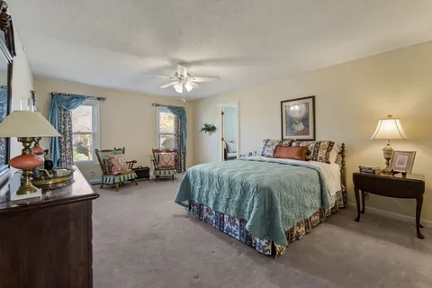 a spacious bedroom with a bed a table and chair