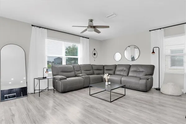 a living room with furniture a wooden floor and a large window