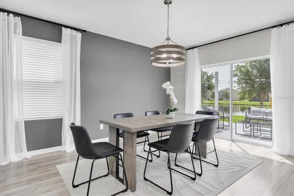 a kitchen with stainless steel appliances a dining table chairs refrigerator and microwave