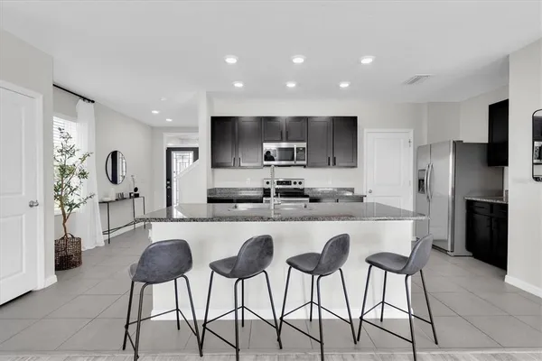 a kitchen with stainless steel appliances granite countertop a stove a sink a microwave a refrigerator and cabinets