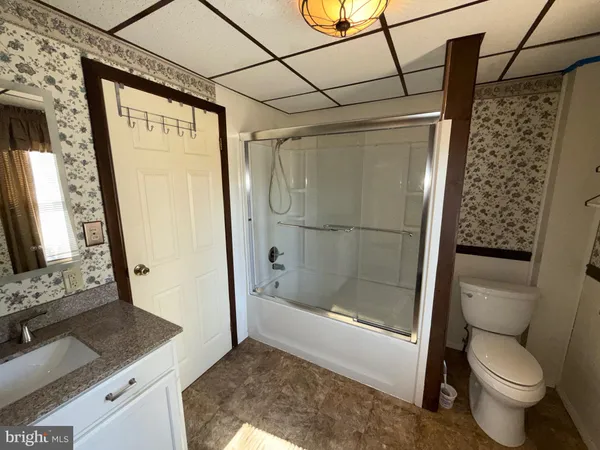 a bathroom with a granite countertop sink a toilet and a shower