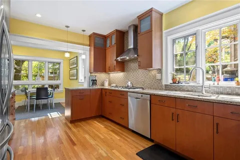 a kitchen with a sink wooden cabinets dining table chairs and a large window