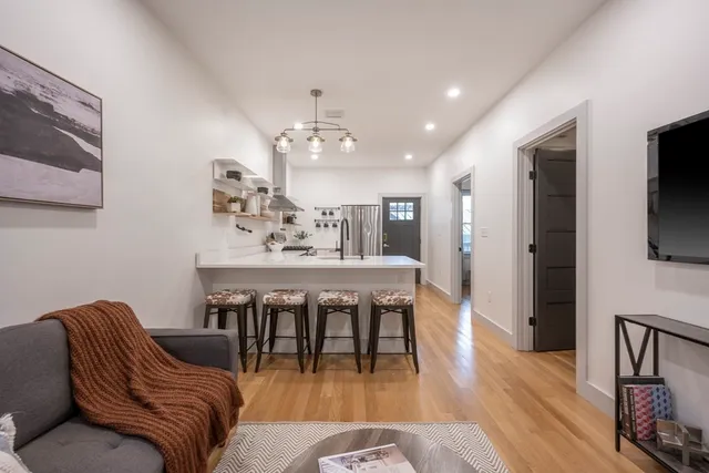 a living room with furniture a flat screen tv and kitchen view