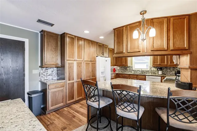 a kitchen with stainless steel appliances granite countertop a stove a refrigerator a dining table and chairs with wooden floor