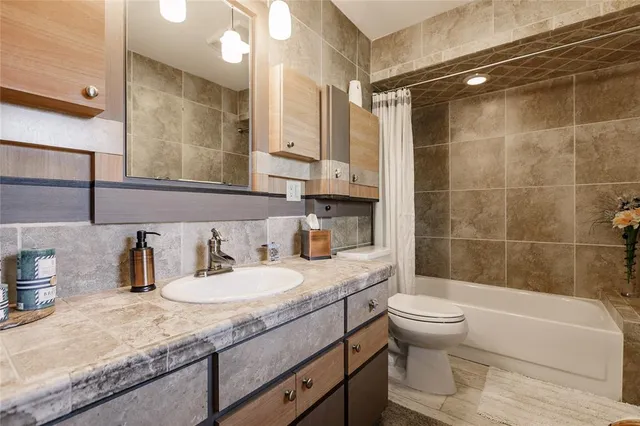 a bathroom with a granite countertop sink a toilet a mirror and shower